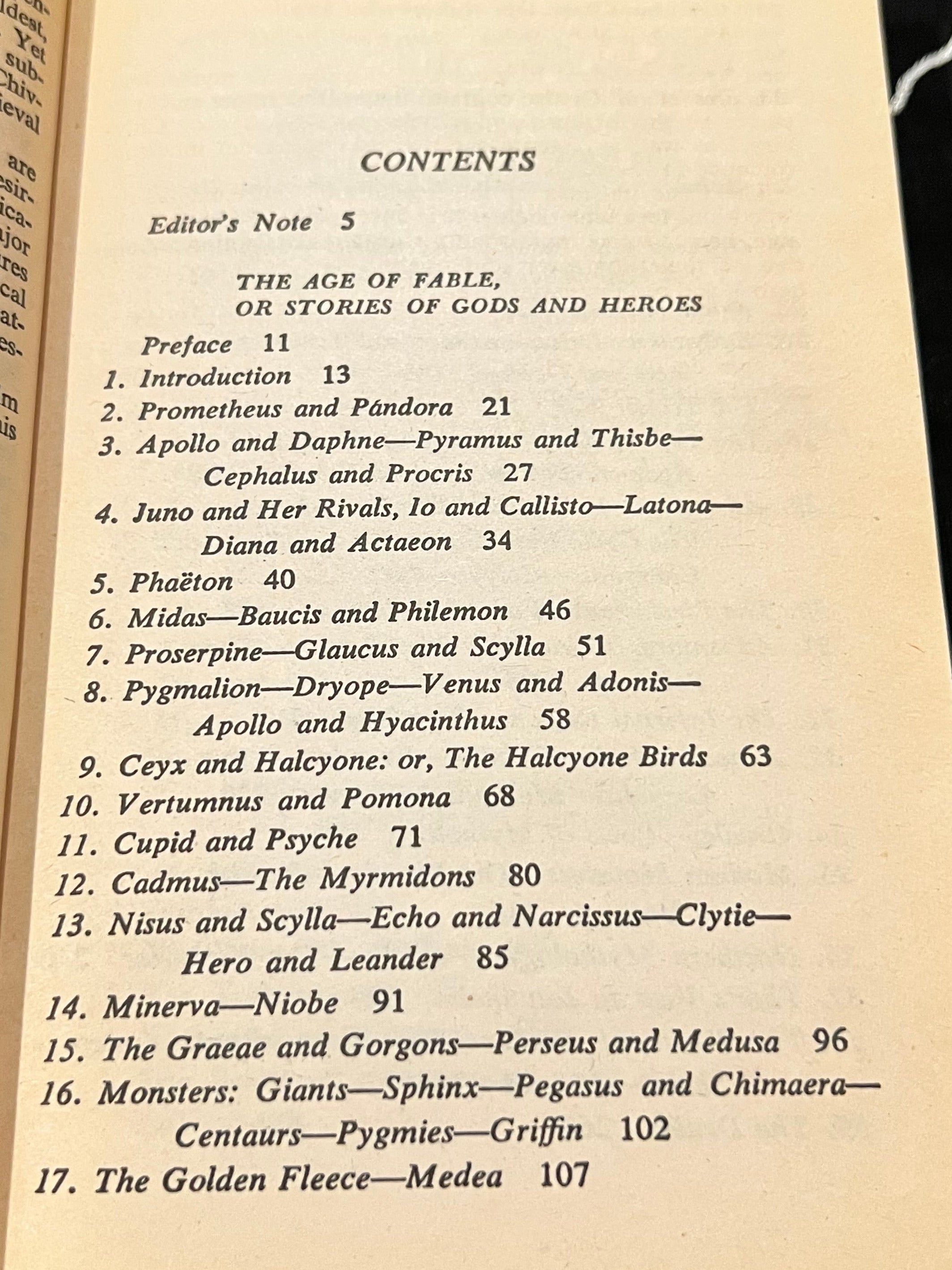 An open printed book or booklet showing the contents page with printed text on aged cream paper, photographed against a dark fabric background with a white decorative object at the lower right.