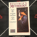 A paperback book of 'Bulfinch's Mythology' by Edmund Fuller, published by Laurel, displayed on a black fabric background with white embroidered patterns.