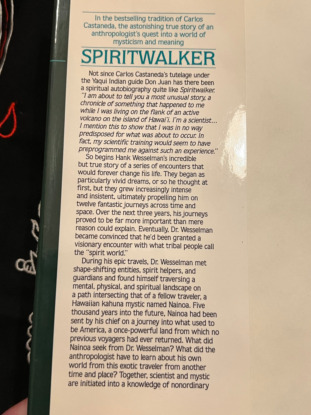 A close-up of a book page featuring the title 'SPIRITWALKER' in large teal text, with a black pen resting on the left side of the page. The page includes a body of text from dust jacket. 