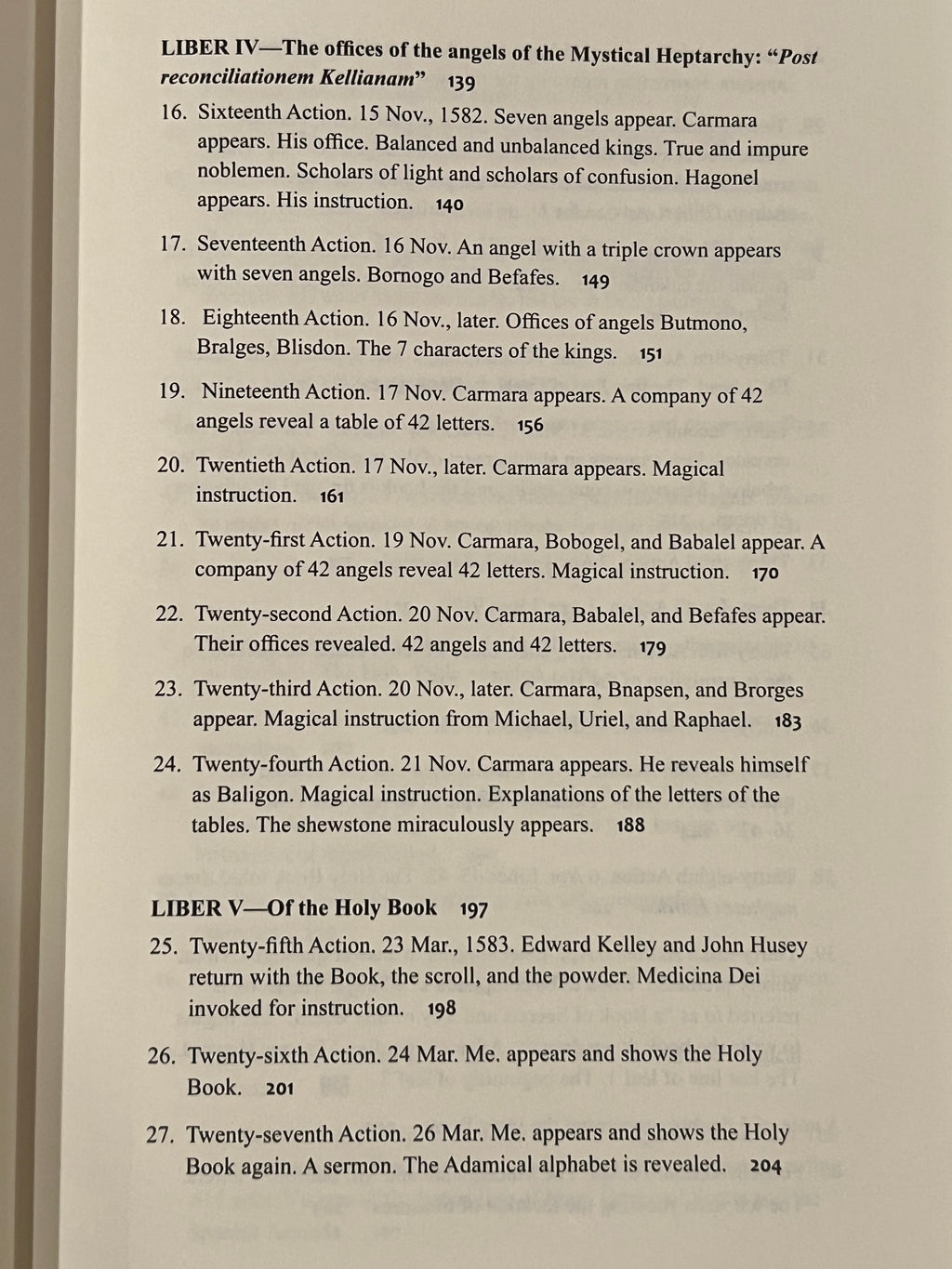 A close-up of an open book's inner pages showing printed text from what appears to be a religious or theological text, with headings 'LIBER IV' and 'LIBER V' and numbered verses.