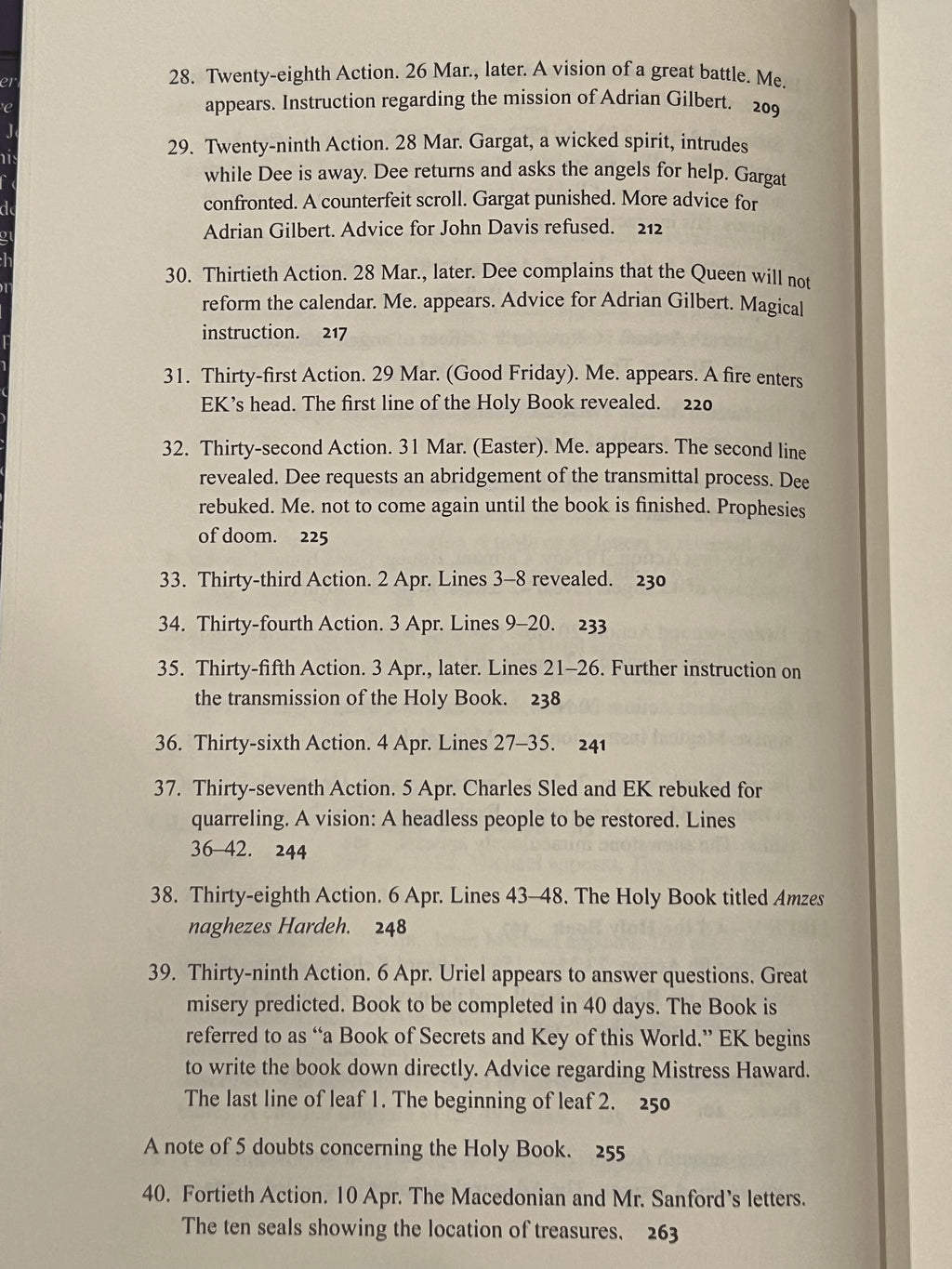 A close-up of an open book showing printed text pages, with the left page turned slightly to reveal both pages and the book's cream-colored paper.