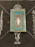 A hardcover book titled 'Spiritwalker: Messages from the Future' by Hank Wesselman, placed on a black cloth with white occult-style illustrations and red symbols.