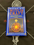 A boxed book titled "Tales of Witch Craft" stands upright on a black cloth with white occult-style line drawings. The box is blue with large orange title text and an illustrated circular mystical design on the front.
