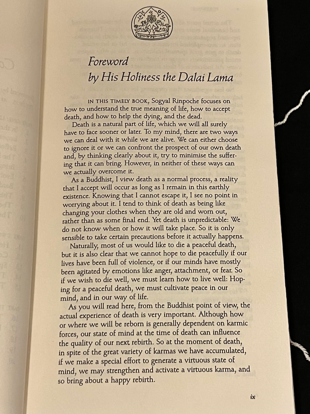 A photographed open book showing a printed foreword page with the title 'Foreword by His Holiness the Dalai Lama' and several paragraphs of black text on warm beige paper.