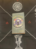 A book titled 'True Magick: A Beginner's Guide' by Amber K, placed on a black cloth printed with white occult-style diagrams and symbols.