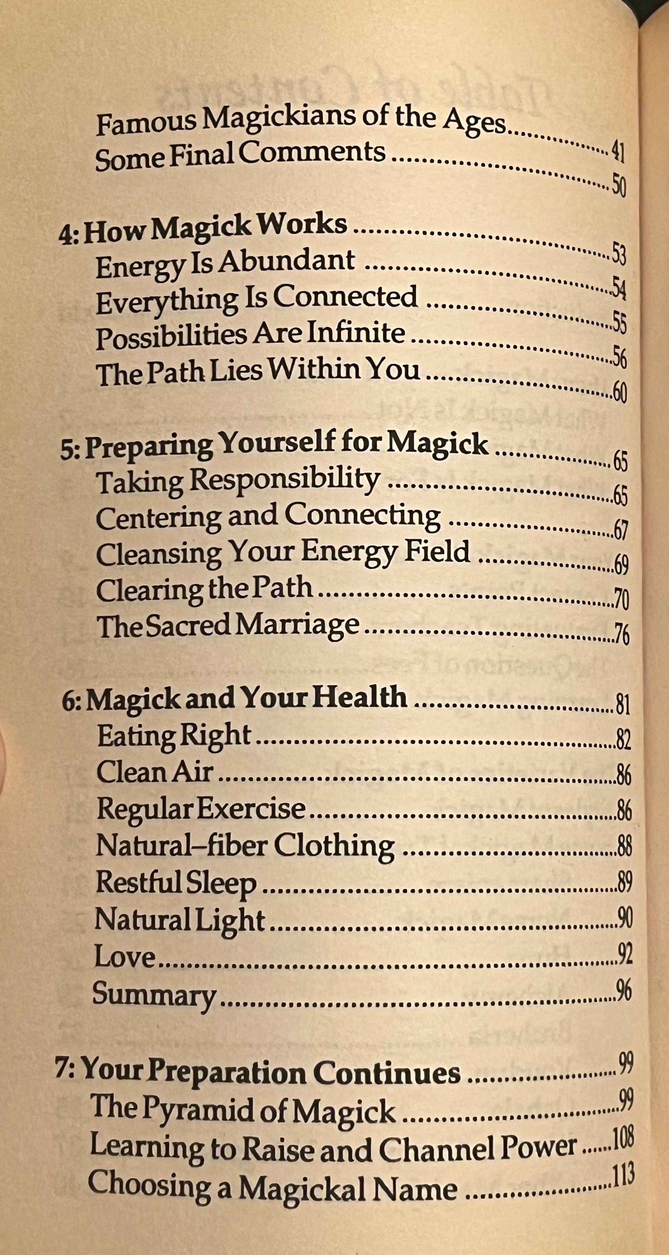 A close-up of an open book showing the table of contents page for a book about magic, with black text on a warm beige paper page.